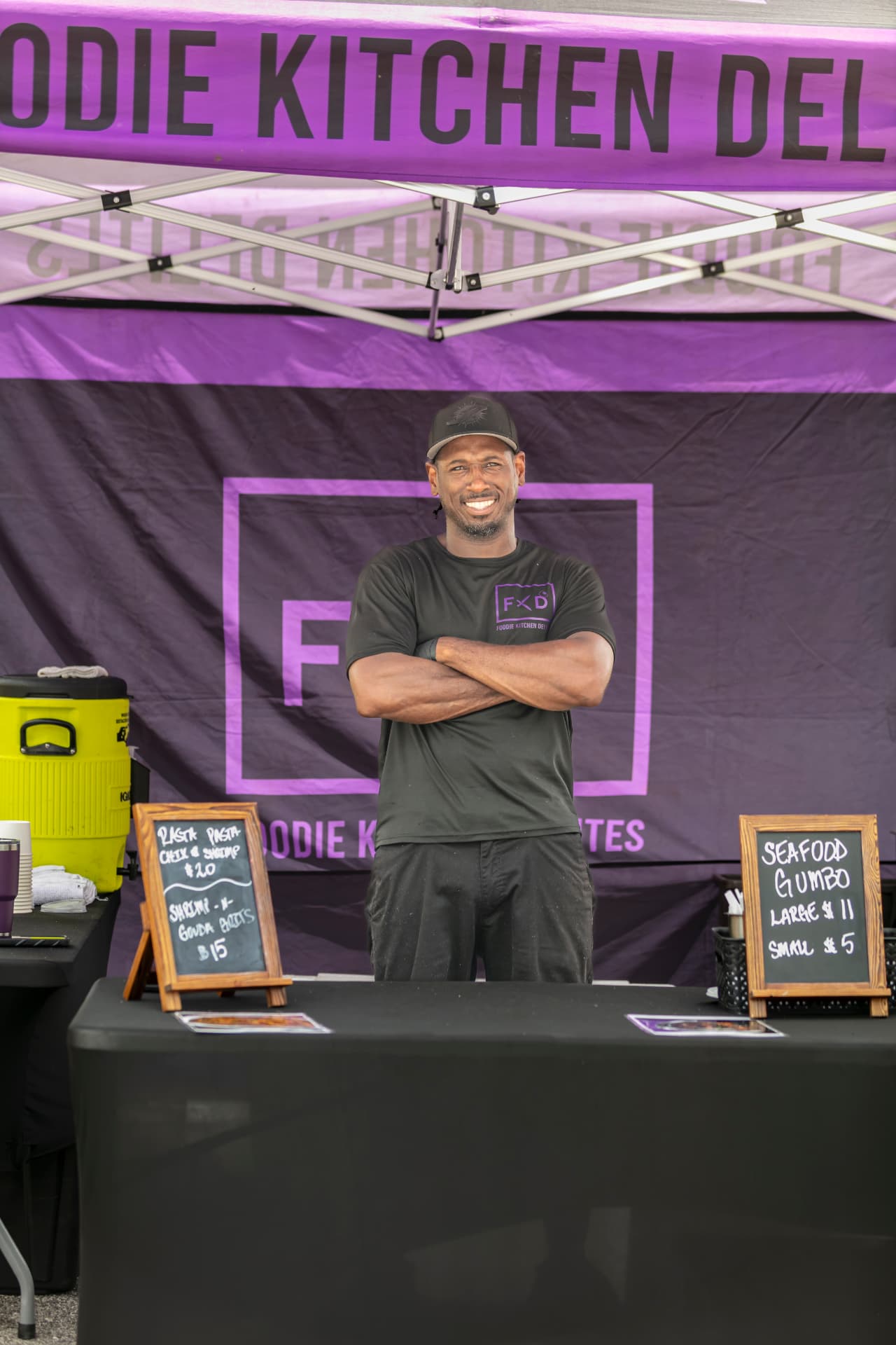 A food vendor preparing orders under a market tent.