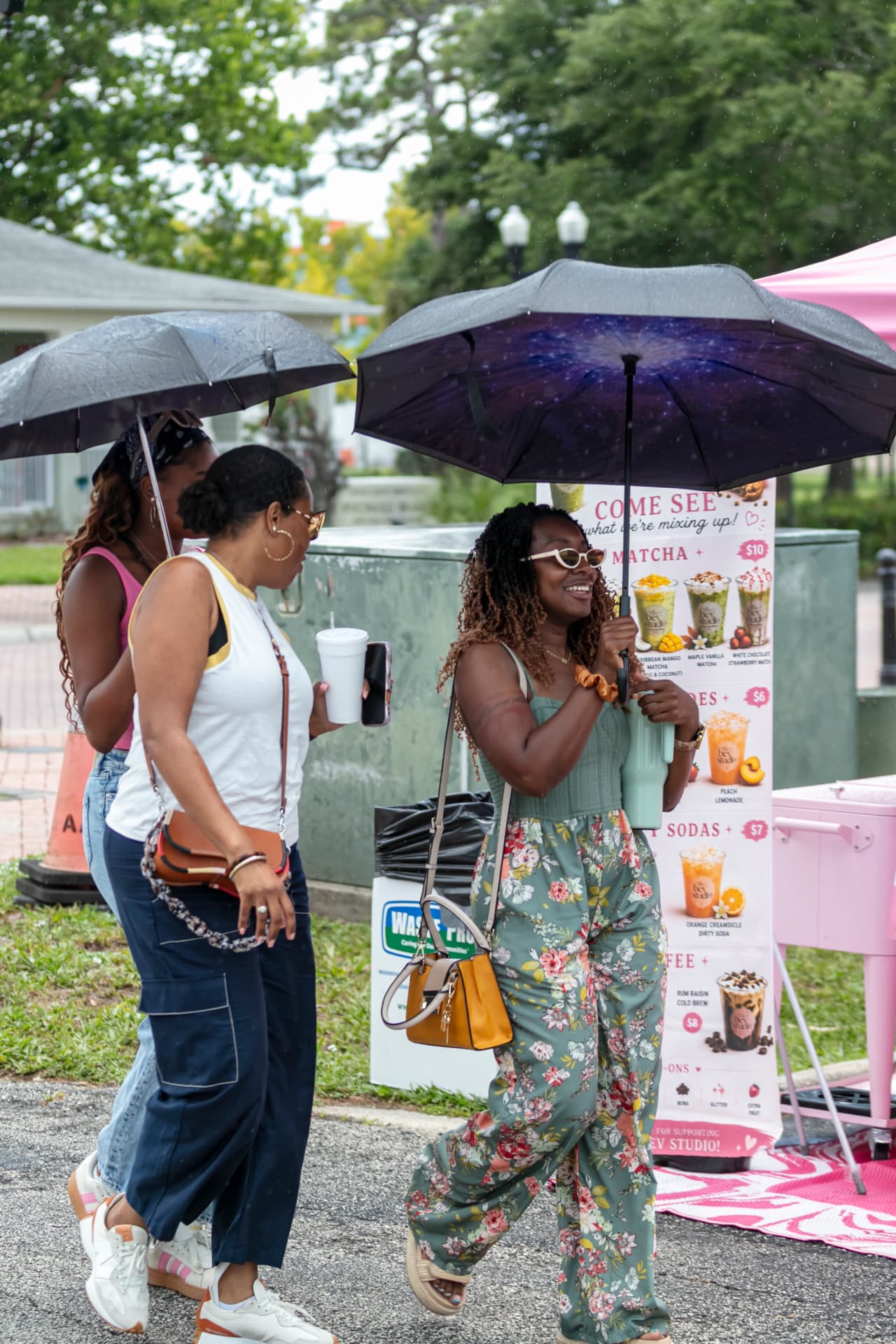 Residents standing together under umbrellas at a community gathering in Historic Eatonville